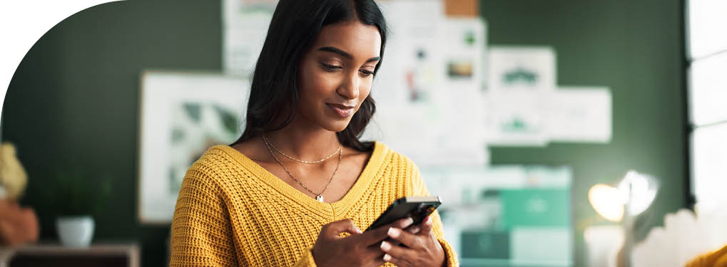 Indian woman, home and smile with smartphone in study room for elearning group and announcement. Female person, university learner and happy on internet with social media interaction and posts